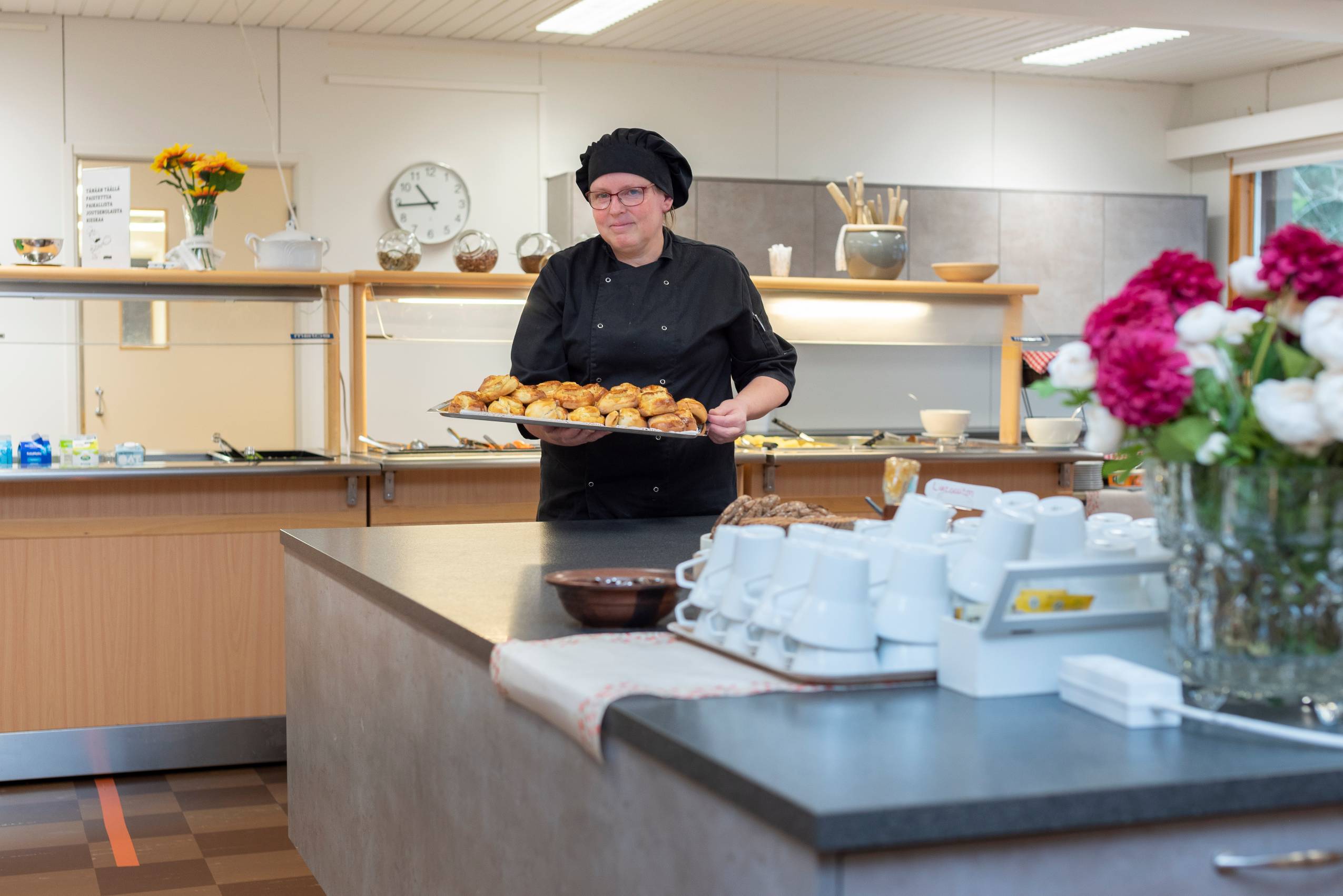 Kuvassa opiston kokki jolla kädessään pullatarjotin